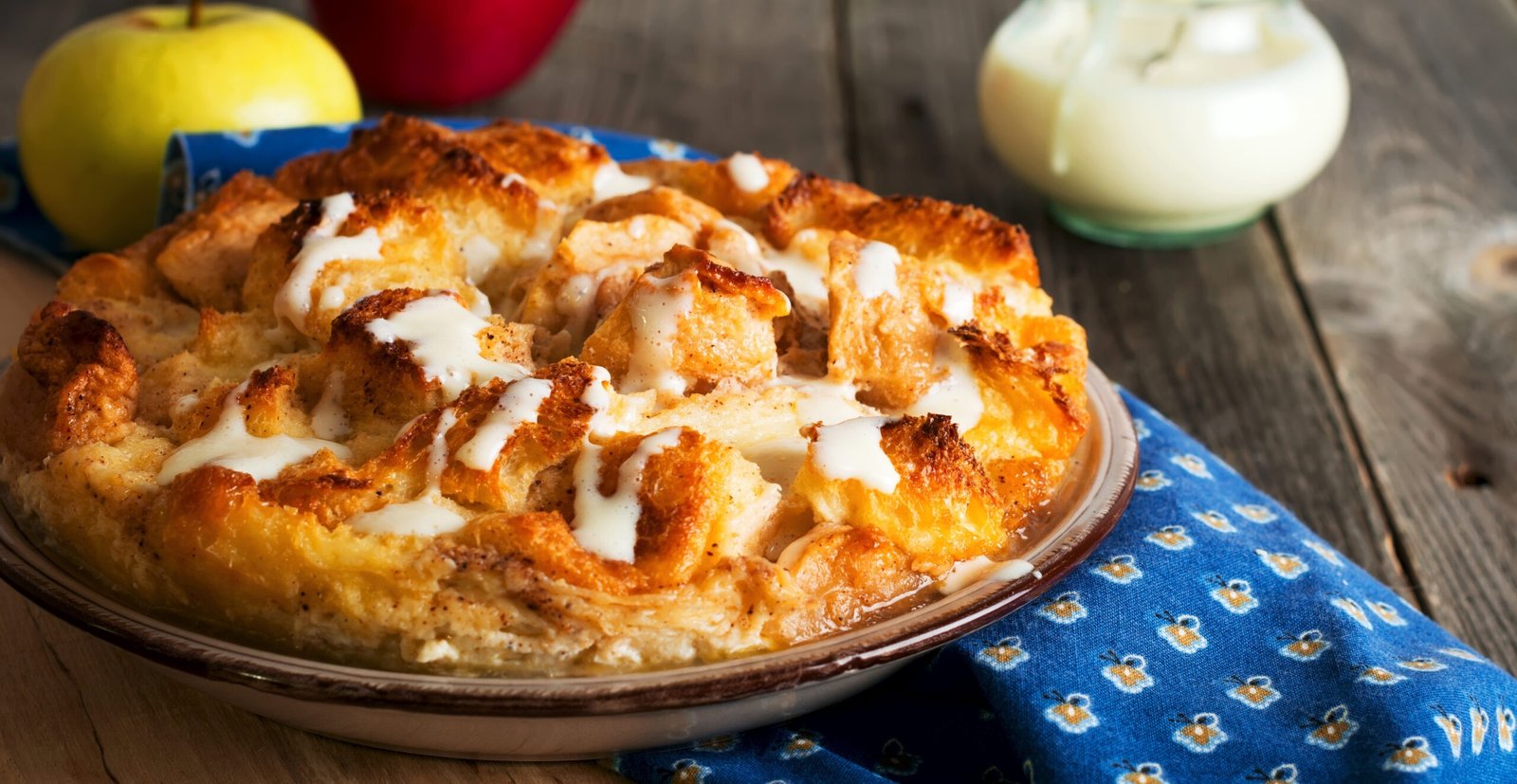 Bread pudding. Traditional English breakfast casserole with apples and vanilla sauce. Bread and butter pudding on old wooden background. Selective focus.