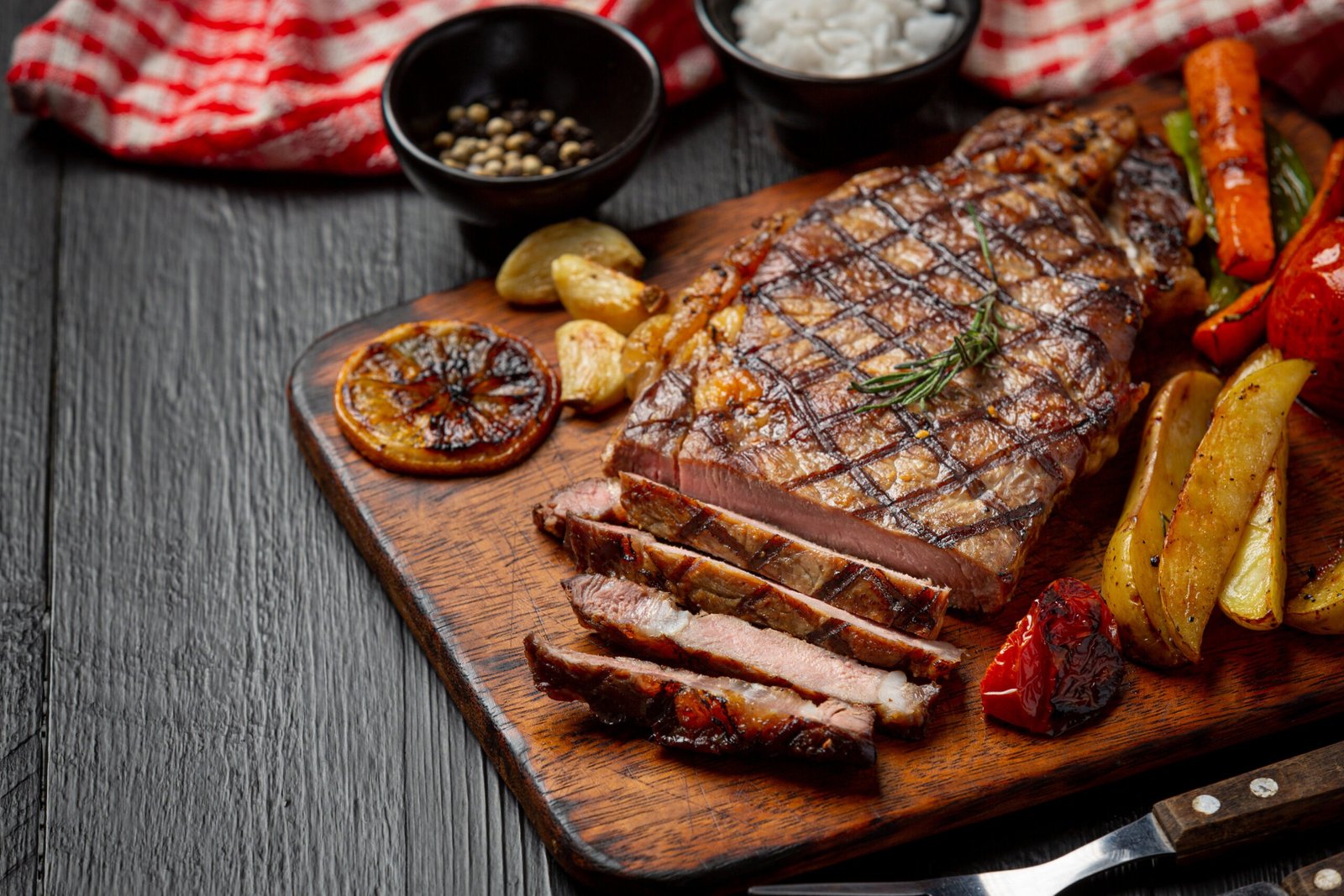 Grilled beef steak on the dark wooden background.