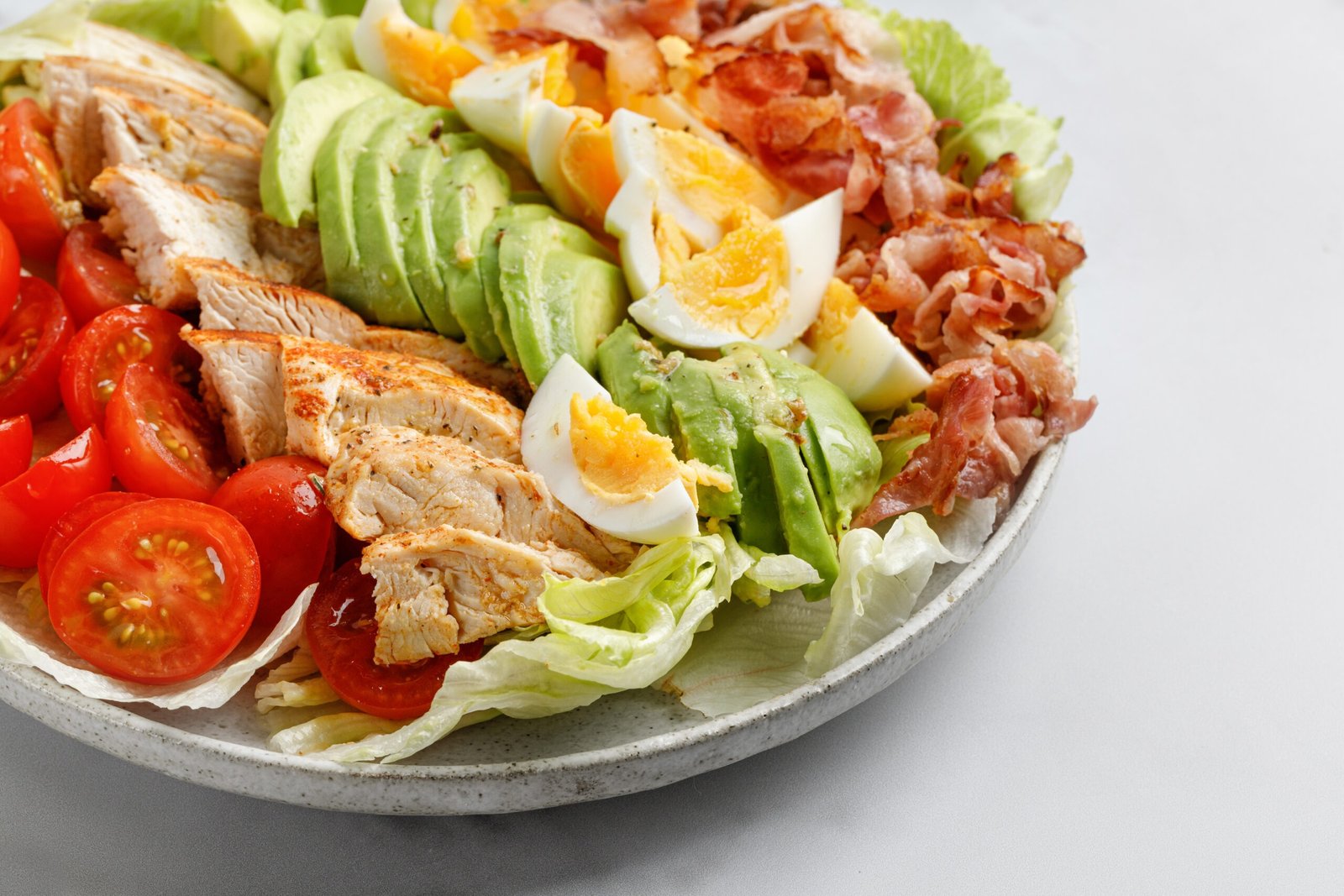 Cobb salad with bacon, avocado, tomato, grilled chicken, eggs isolated on  white background. American salad. Healthy food.