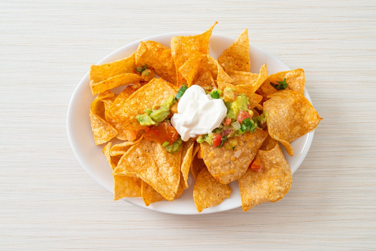 Mexican nachos tortilla chips with jalapeno, guacamole, tomatoes salsa and dip