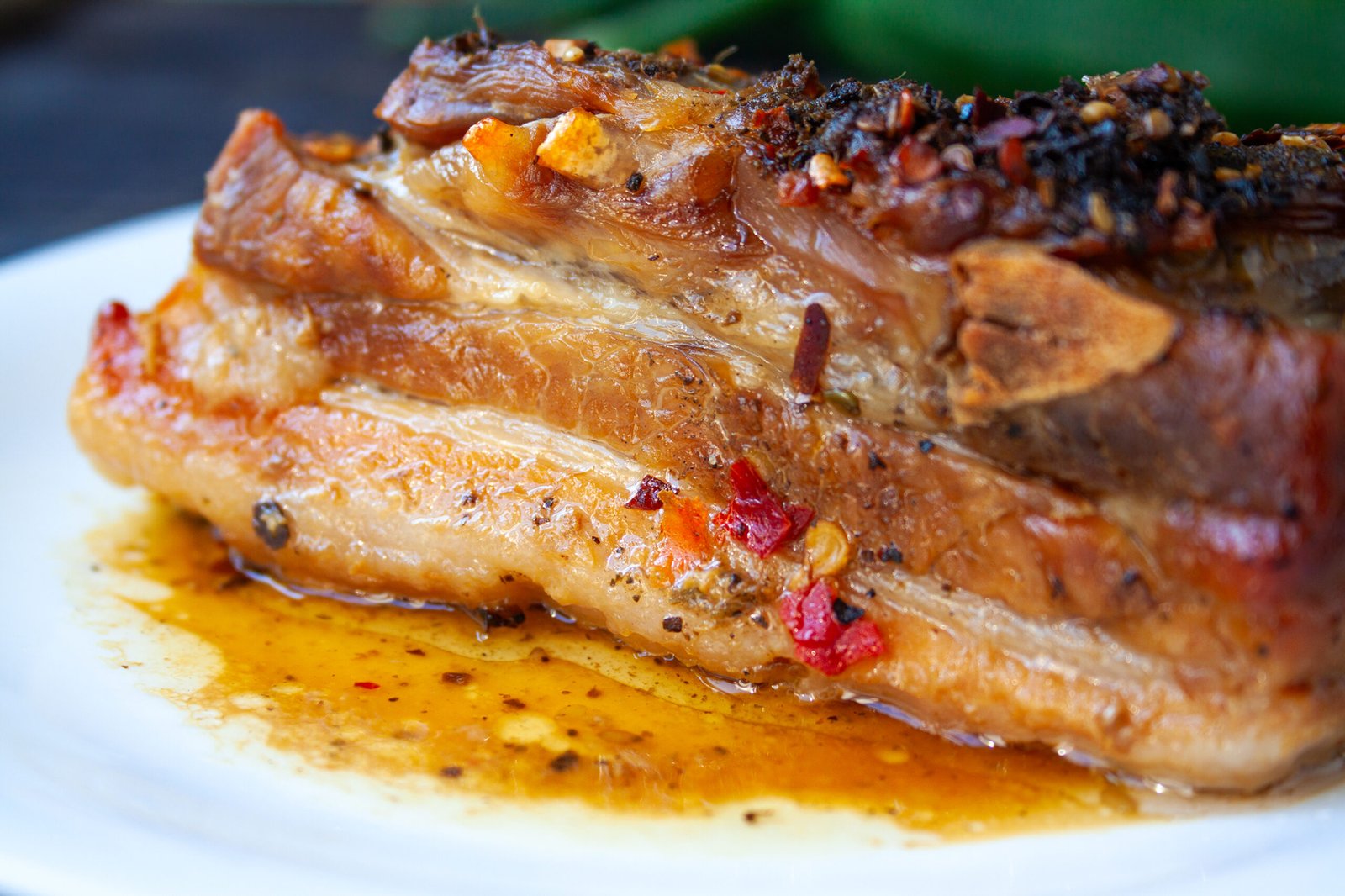 Spicy fried brisket with interlayers of pork lard, baked with herbs and spices, close-up on a white plate