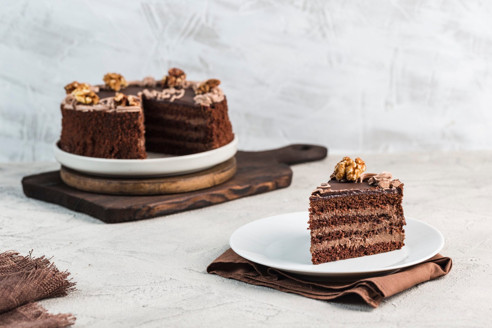 Chocolate sponge cake on a light background in the cut and the piece on the plate, horizontal orientation close up. Dessert for birthday and holiday.