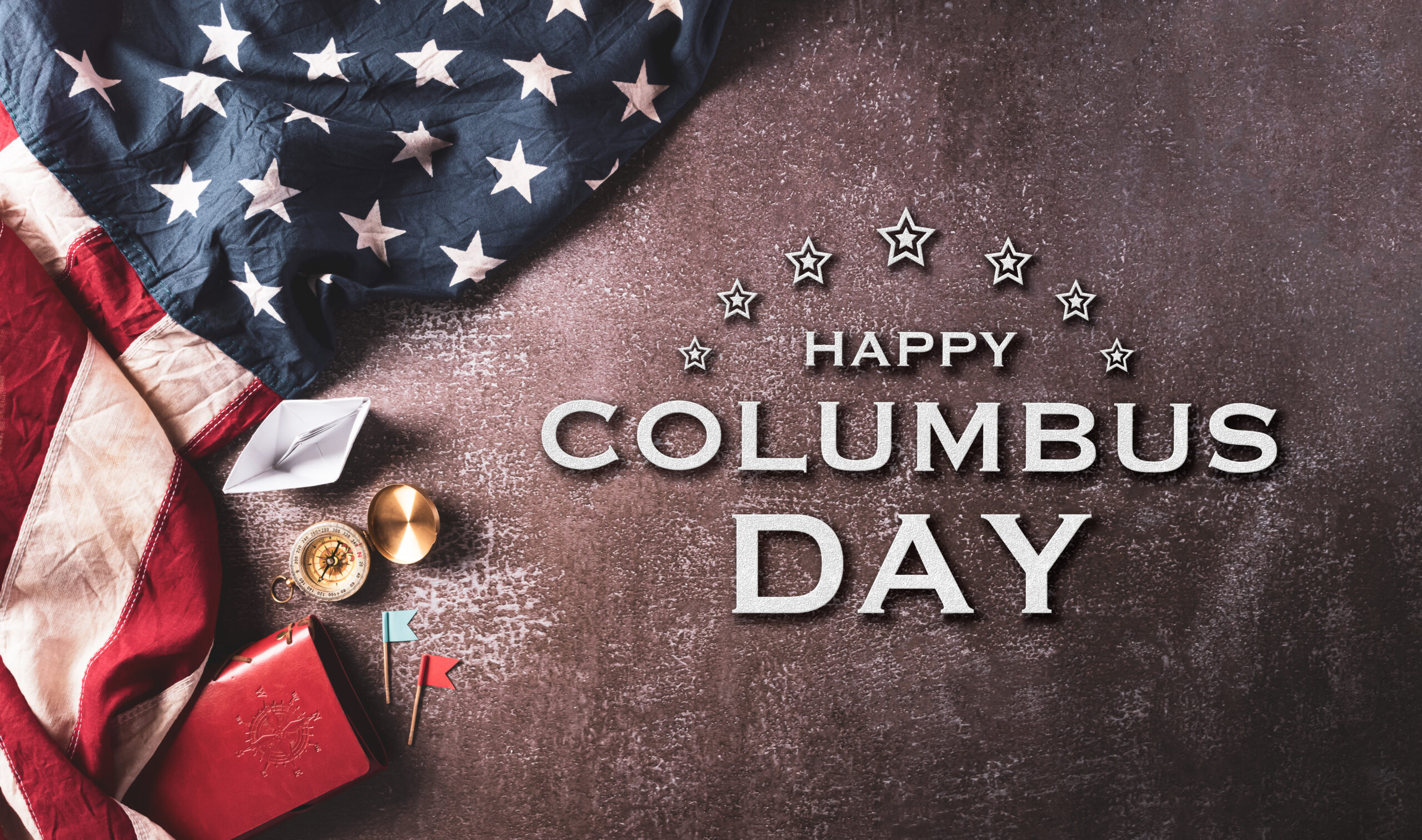 Happy Columbus Day concept. Vintage American flag, compass, paper boat, rope with the text on dark stone background.